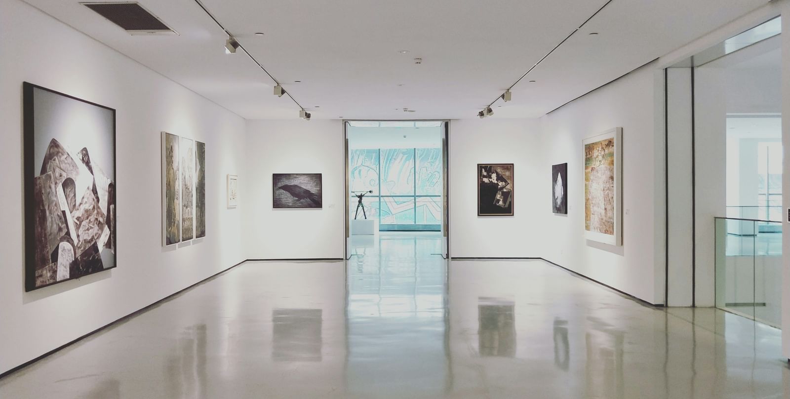 An overview of a empty museum with paintings hung on the walls.