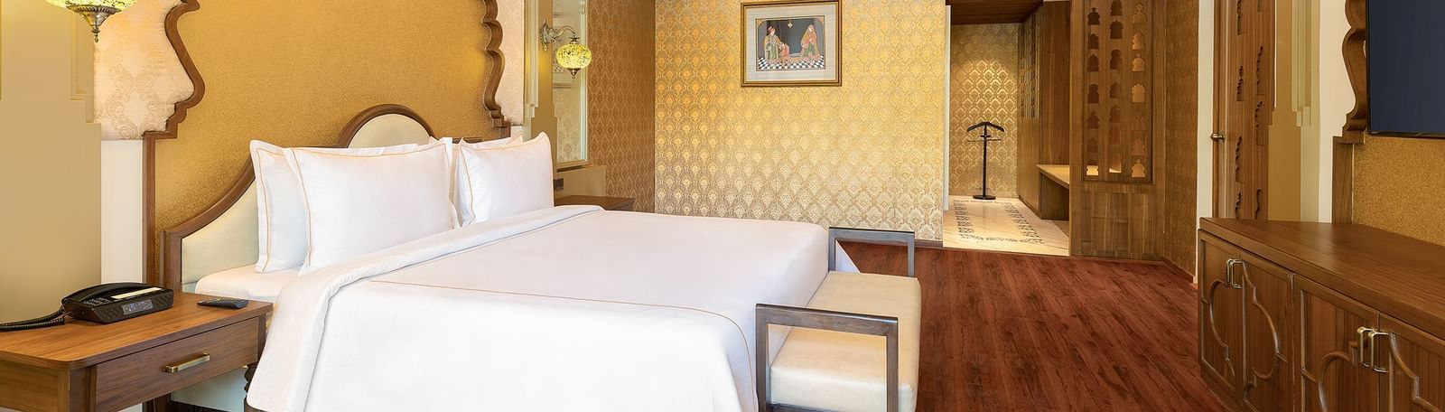 A spacious bedroom with clean white linen and ornate gold frames above the beds – Kaldan Samudra, one of the best luxury hotels in Mahabalipuram
