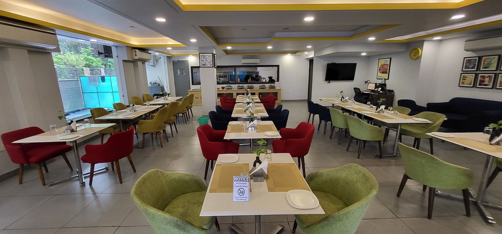 An image of a restaurant at Inde Hotel Golf Course Extension featuring several sets of chairs and tables where plates and table mats are placed