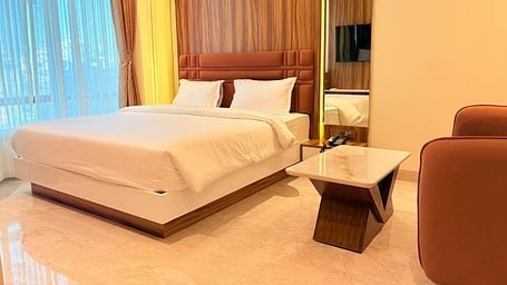 A bed with a wooden headboard and a television reflected in the mirror at Hotel Mumbai House, Vashi.