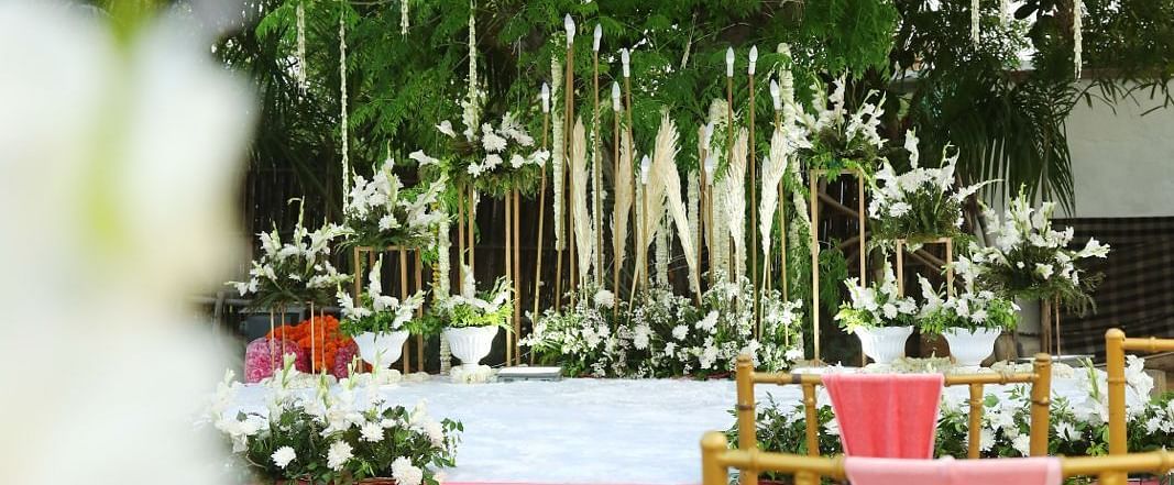 A decorated outdoor space at Tisya Farms, Gurgaon with hanging lights, floral elements, and pink table setups.