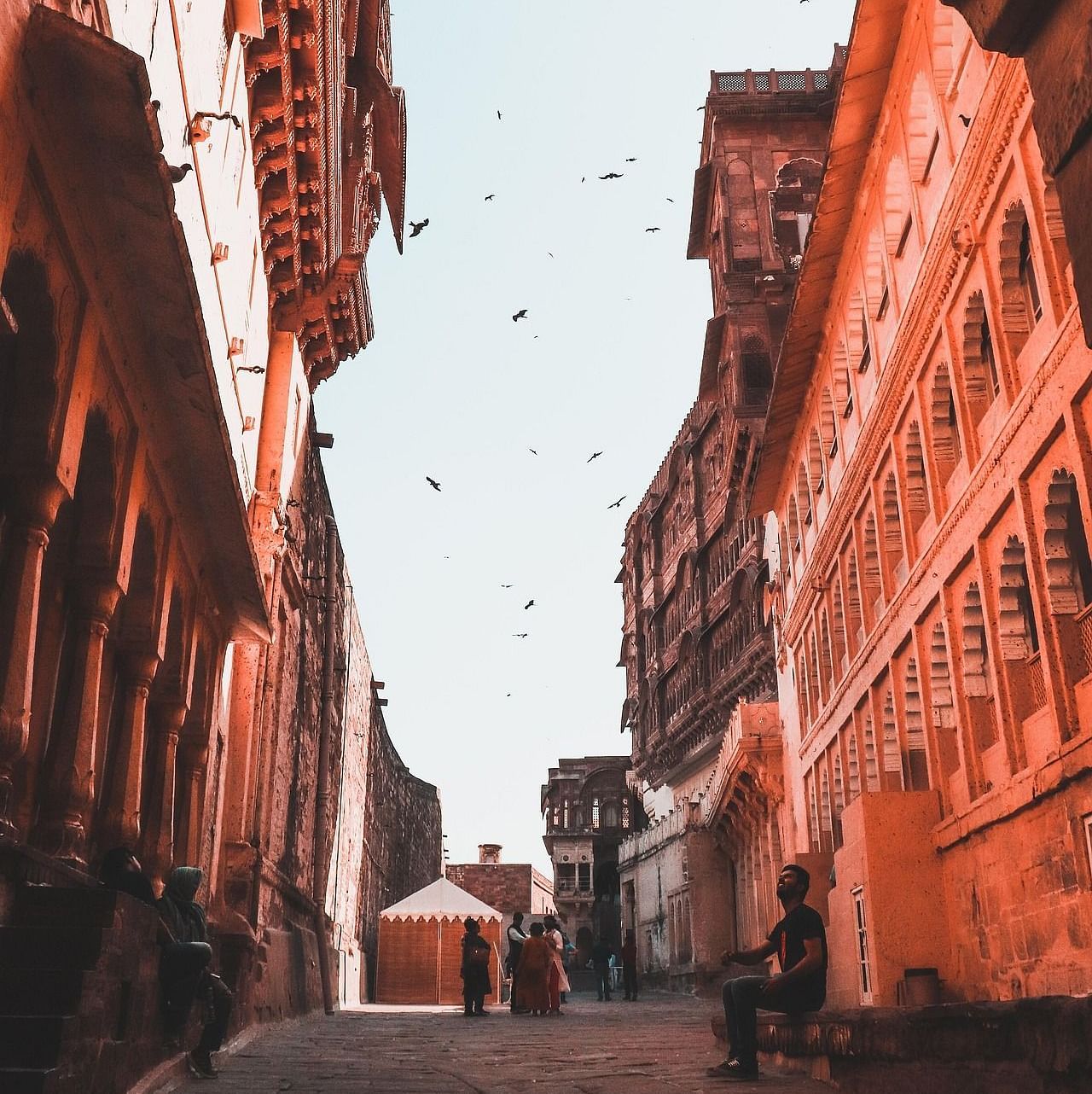 A pathway with historical buildings and people in the background.