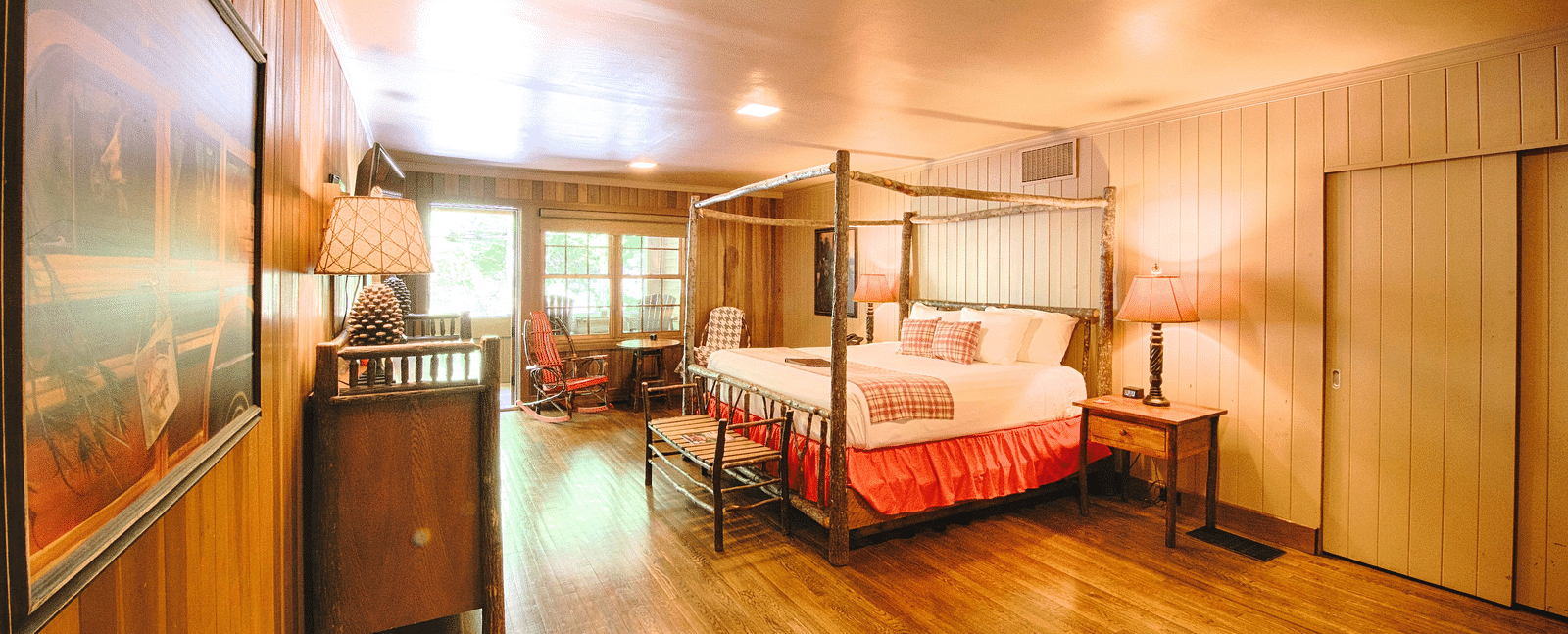 corner view image of a bedroom with a wall mounted picture along with a double bed and a door allowing bright natural light into the room - Historic Tapoco Lodge