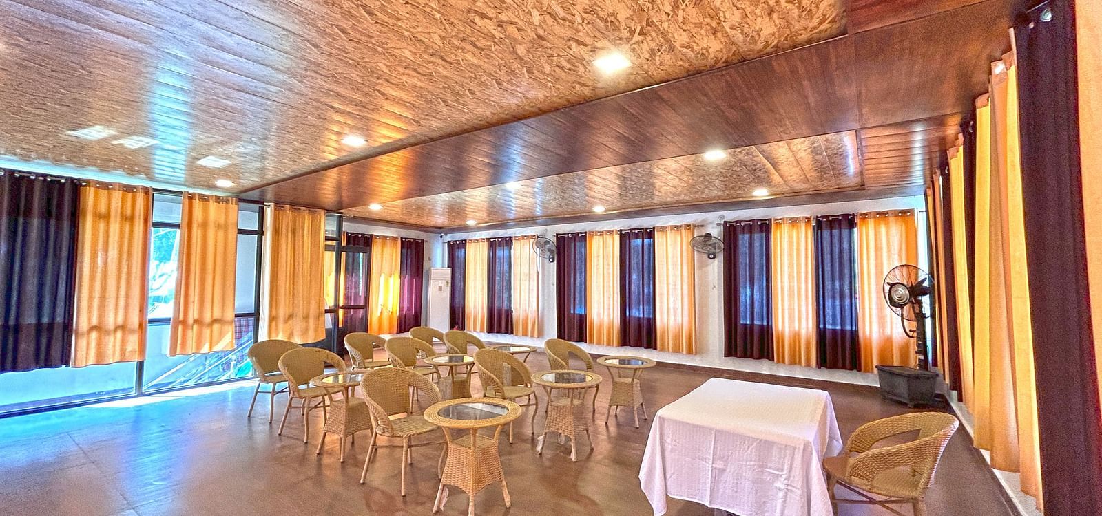 A conference hall with ambient lighting and chairs facing a white table at DLS MJ River Resort, Rishikesh.
