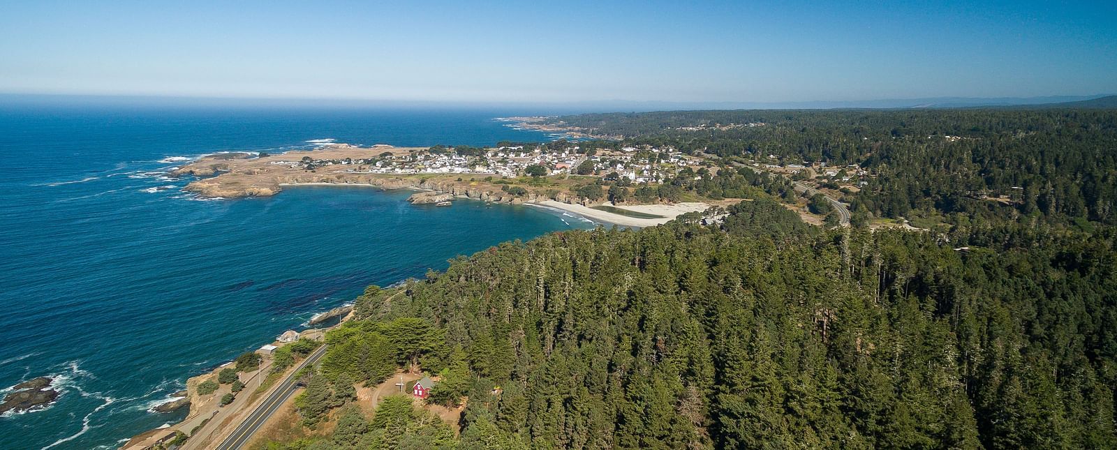 A panoramic of the Mendocino Bay seen from the air with lush green forest its right - Brewery Gulch Inn & Spa