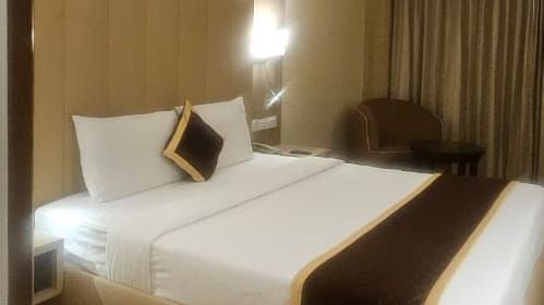Modern hotel room interior with comfortable bedding and warm lighting at La Classic, Hosur Road.