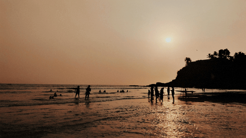 A beach scene in Goa, India with palm trees in the background and people in the foreground.