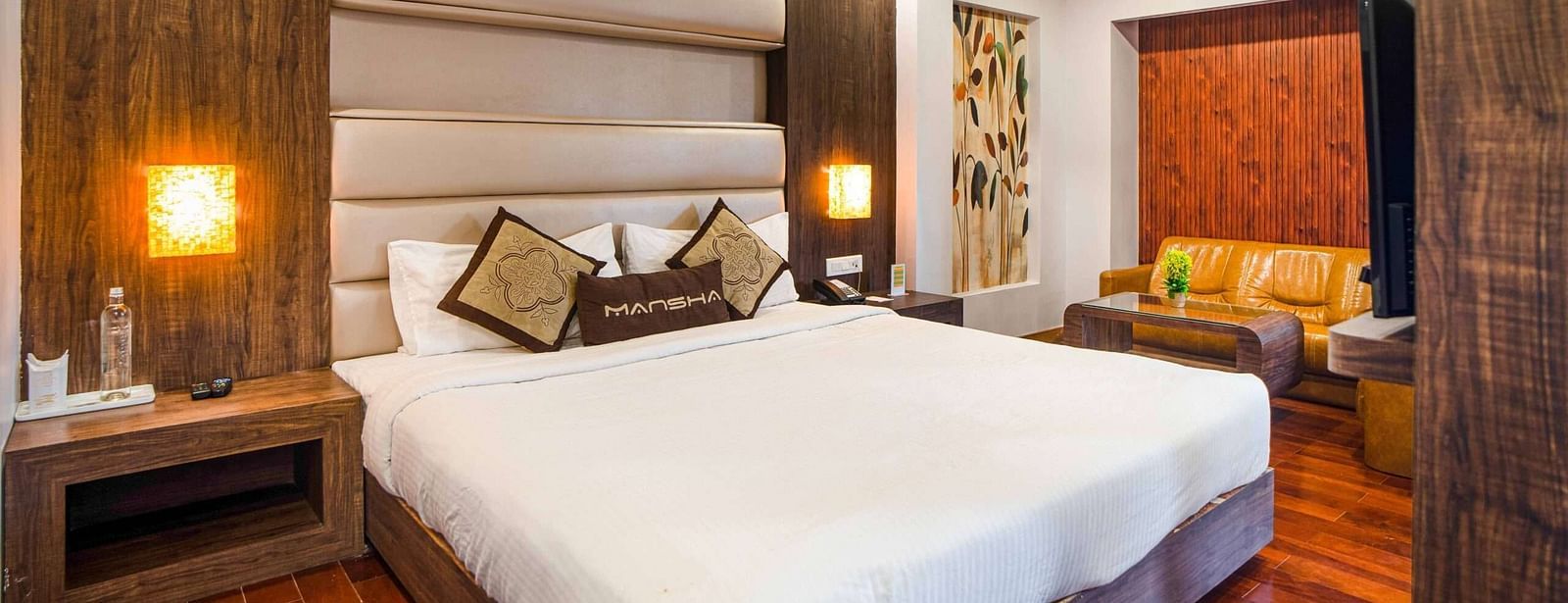 A room at Mansha Hotel Regency featuring a bed with a large headboard, bedside table, and other room amenities.