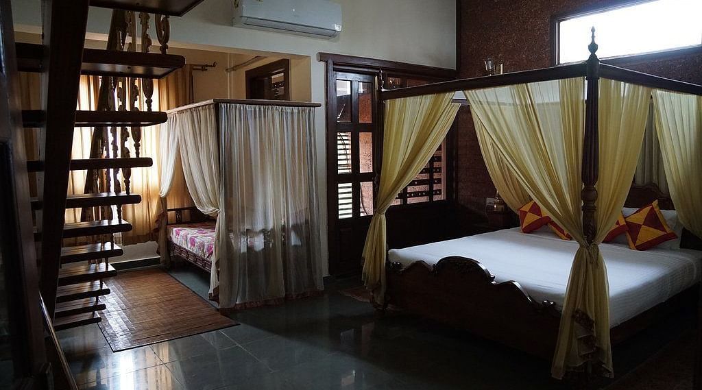 image of the bedroo of malnad attic suite featuring a four poster bed and a day bed at hoysala village resort in hassan