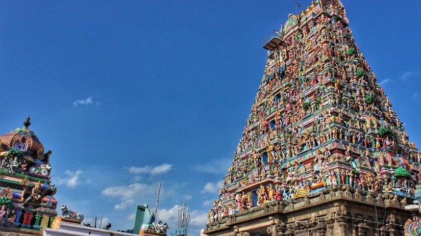 A South Indian temple adorned with intricate sculptures and carvings against a bright blue sky
