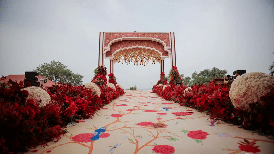 A wide-angle shot of the wedding decorations at the Barbeque Lawn featuring a floral carpet on the aisle at Noor-Us-Sabah Palace, Bhopal.