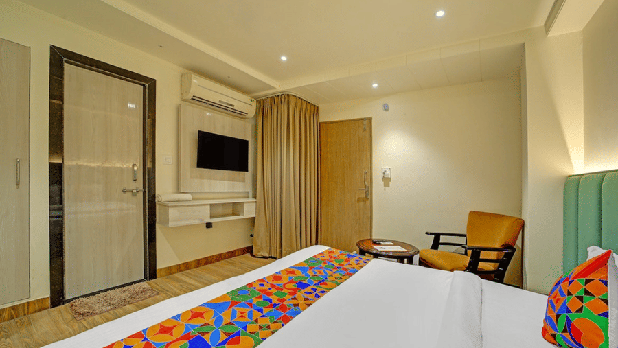 Spacious guest room with work desk, wall-mounted TV and elegant interiors at Hotel Maurya, Bhopal.