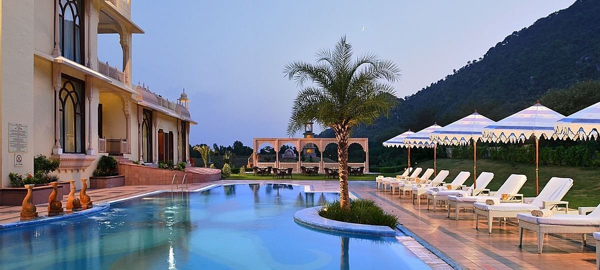Image of the pool at Rajasthali Resort & Spa Jaipur with lounge chairs on the side.