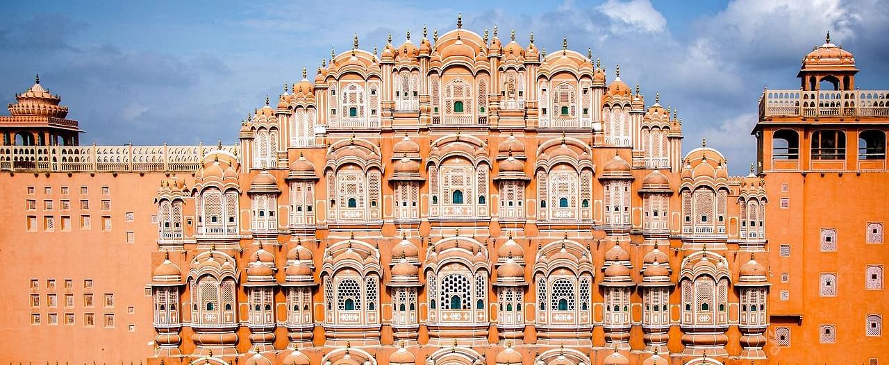Hawa Mahal, Jaipur, with its distinctive pink facade and numerous small windows, under a blue sky.