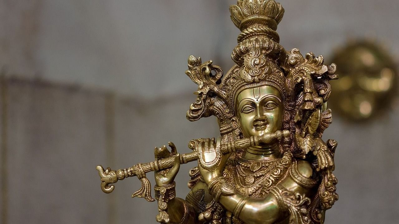 Golden statue of Lord Krishna playing the flute with intricate detailing.
