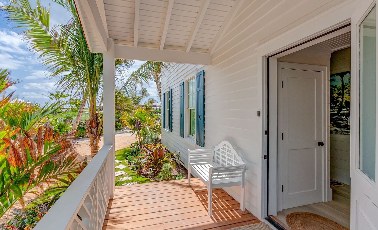 Covered porch with tropical plants and an entrance to the building | Abaco Inn