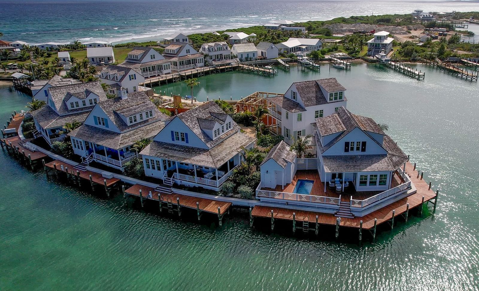Drone view of villas and bungalows built over water with wooden decks, forming a semi-circle above a calm bay | Abaco Inn