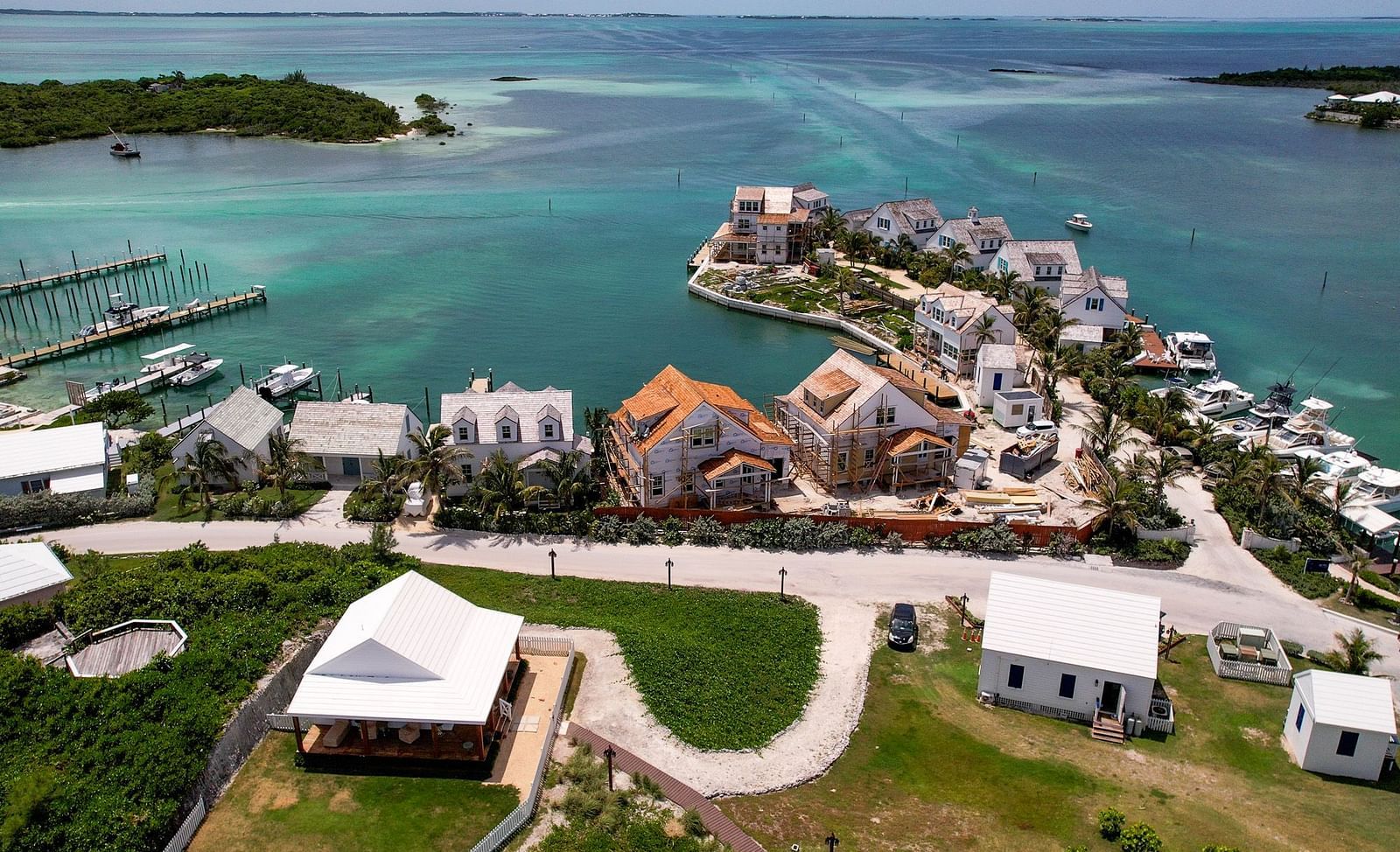 Aerial shot of a coastal resort with clustered villas, green landscaping, and a winding waterfront promenade | Abaco Inn