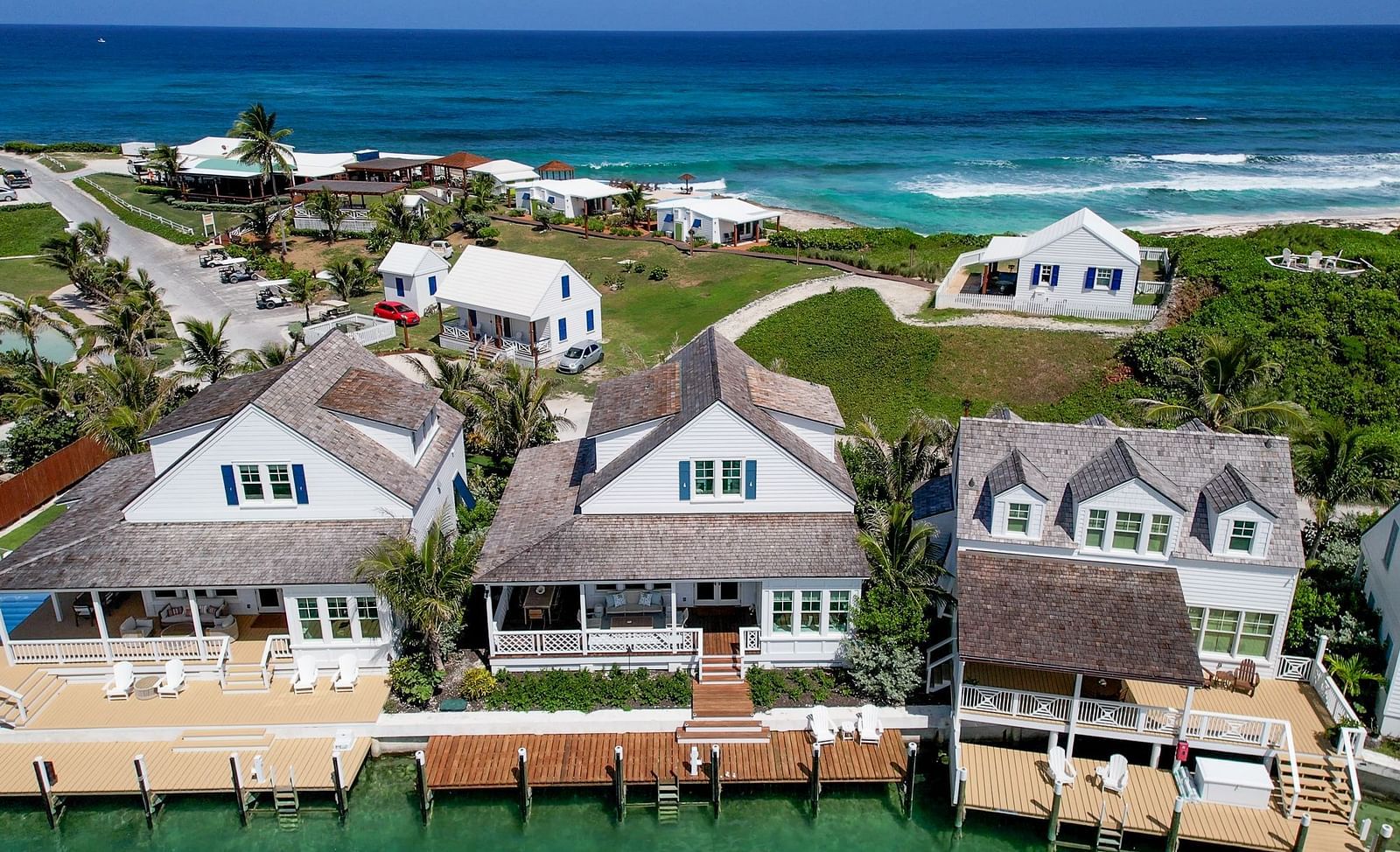 A coastal settlement of Abaco Inn, featuring numerous houses with light-colored roofs nestled among abundant vegetation, bordering an expansive body of water 