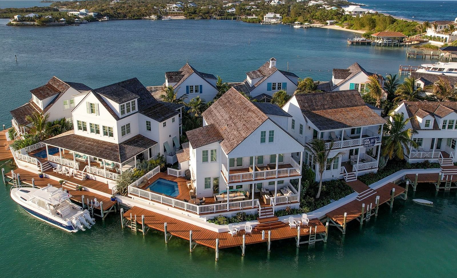 Aerial view of luxurious waterfront houses with private docs, swimming pools and a boat docked nearby at Abaco Inn.