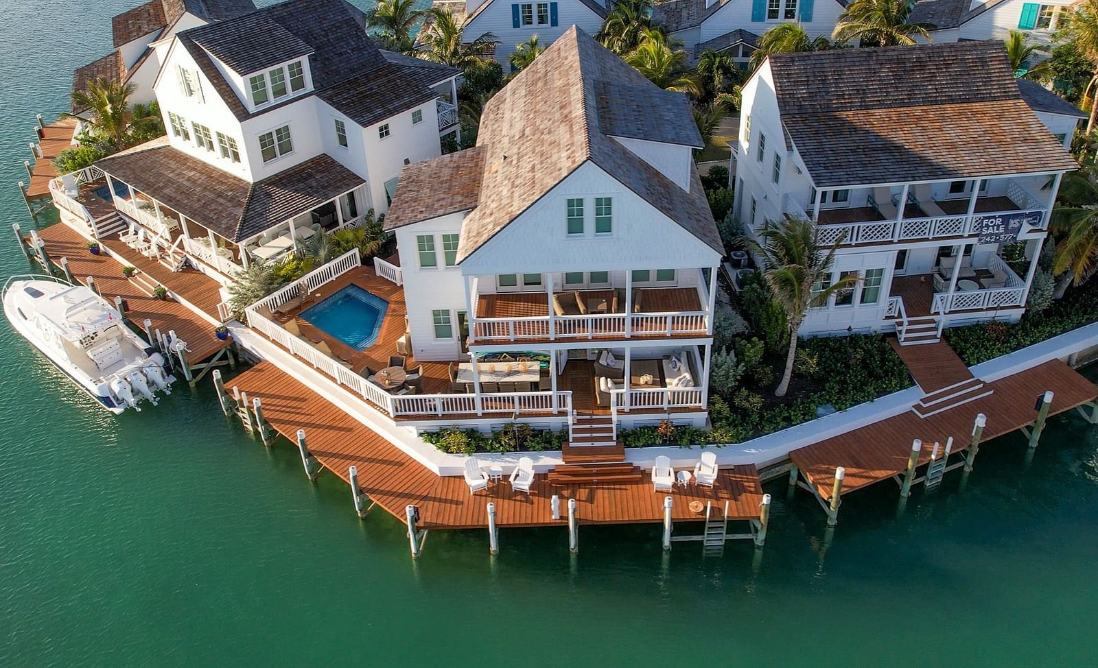 Aerial view of luxurious waterfront houses with private docs, swimming pools and a boat docked nearby at Abaco Inn.