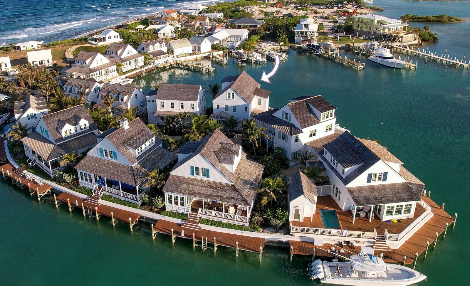 Aerial view of luxurious waterfront houses with private docs, swimming pools and a boat docked nearby at Abaco Inn.
