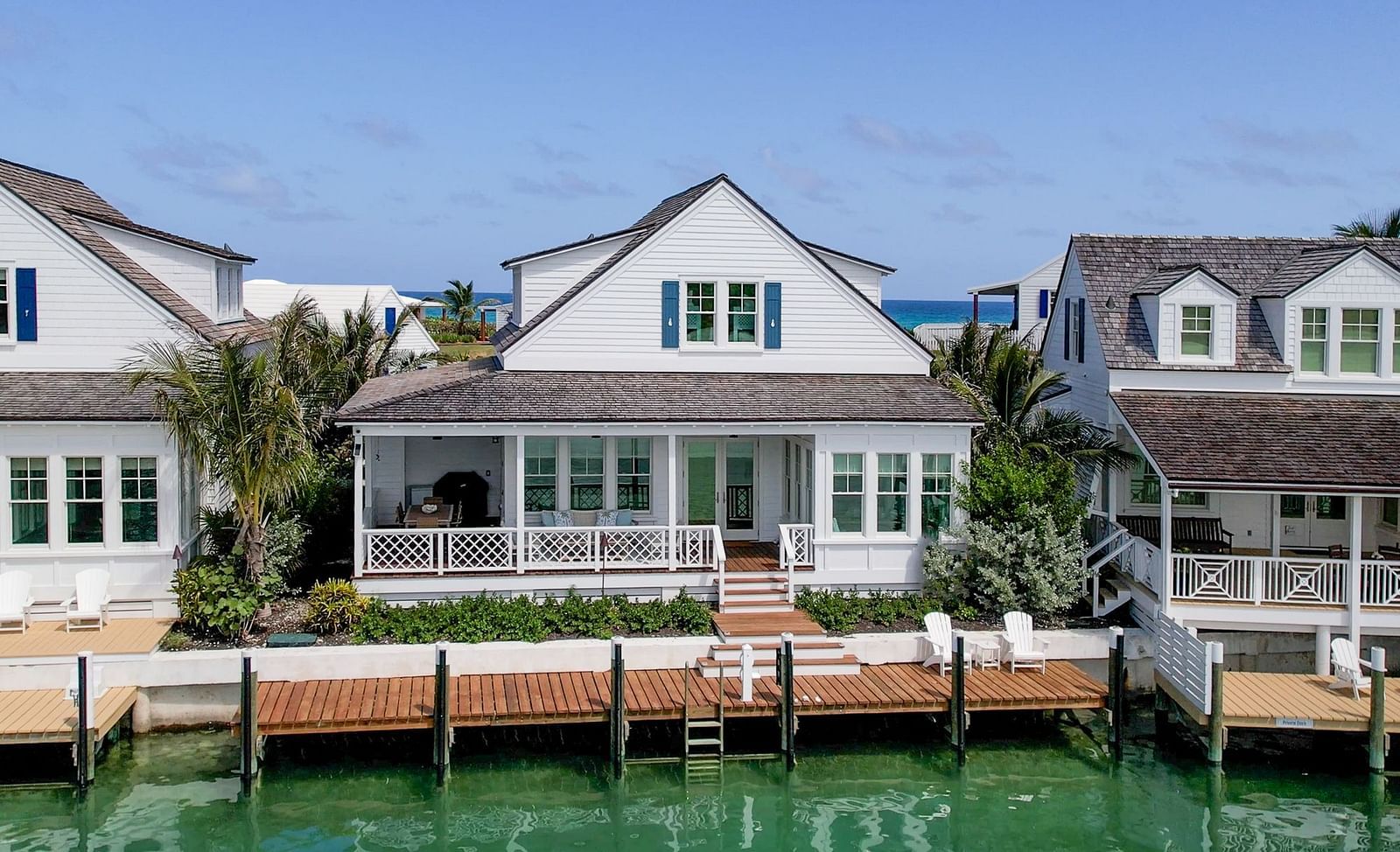 A cluster of well-maintained houses of Abaco Inn situated directly on the waterfront, with calm water in the foreground reflecting the clear sky