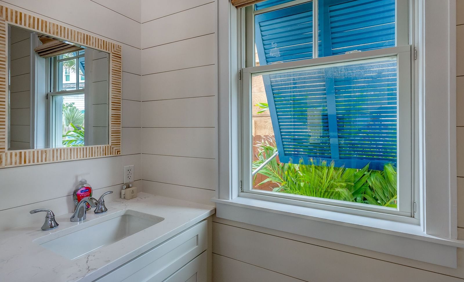 Bathroom with a window, vanity, and decorative mirror | Abaco Inn