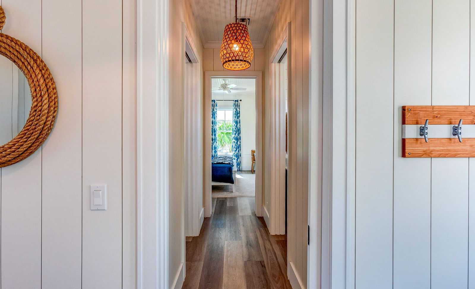 Hallway with wooden flooring, white panelled walls, and a hanging light fixture | Abaco Inn