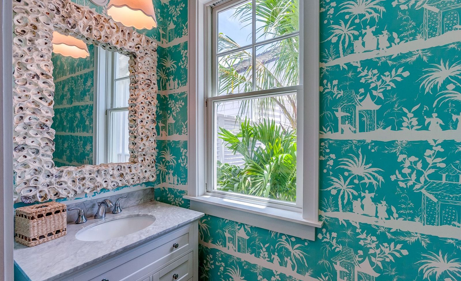 Bathroom with turquoise wallpaper, a vintage mirror, and natural light | Abaco Inn
