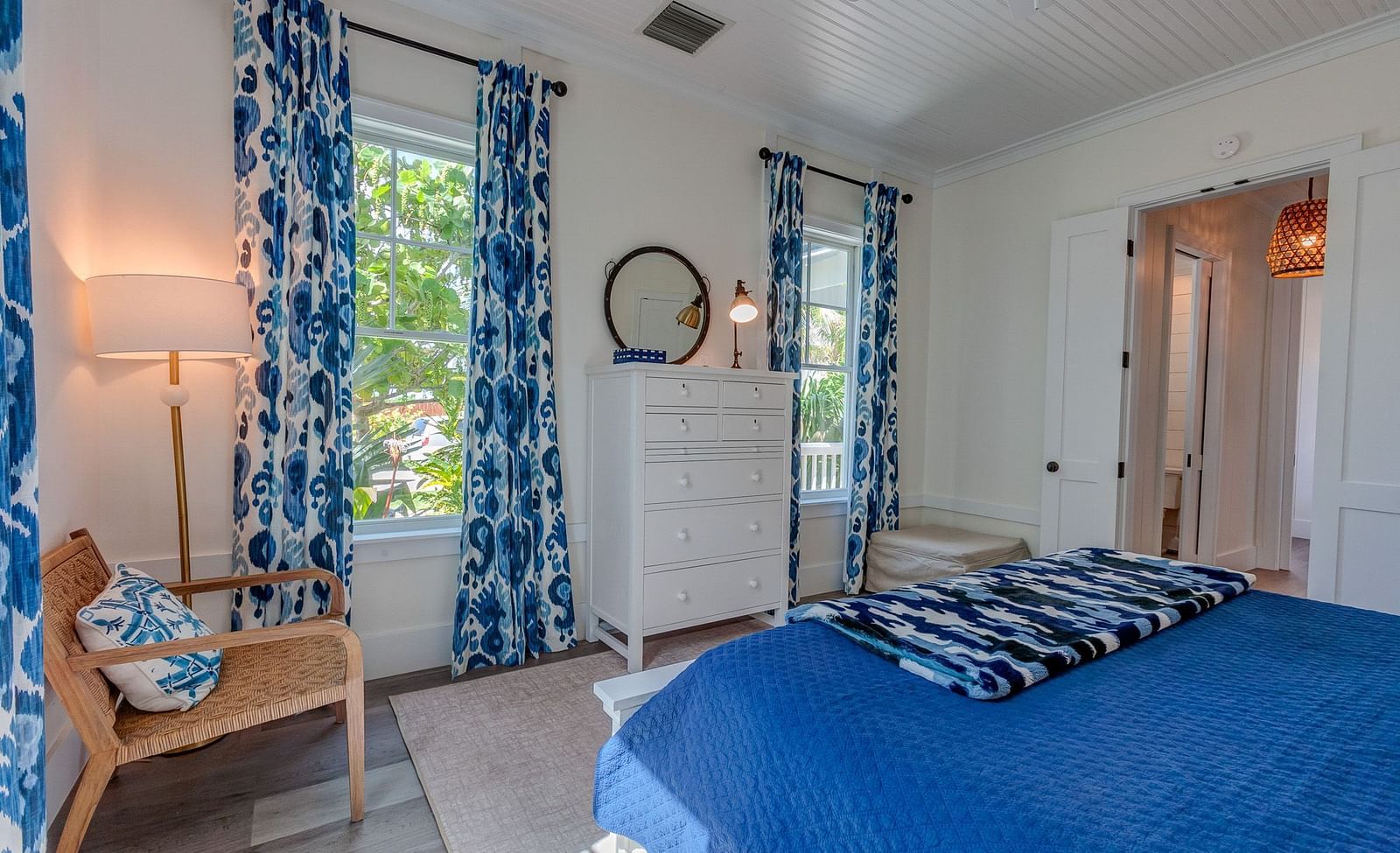 Bedroom with blue curtains, a wooden chair, and a cozy bed | Abaco Inn