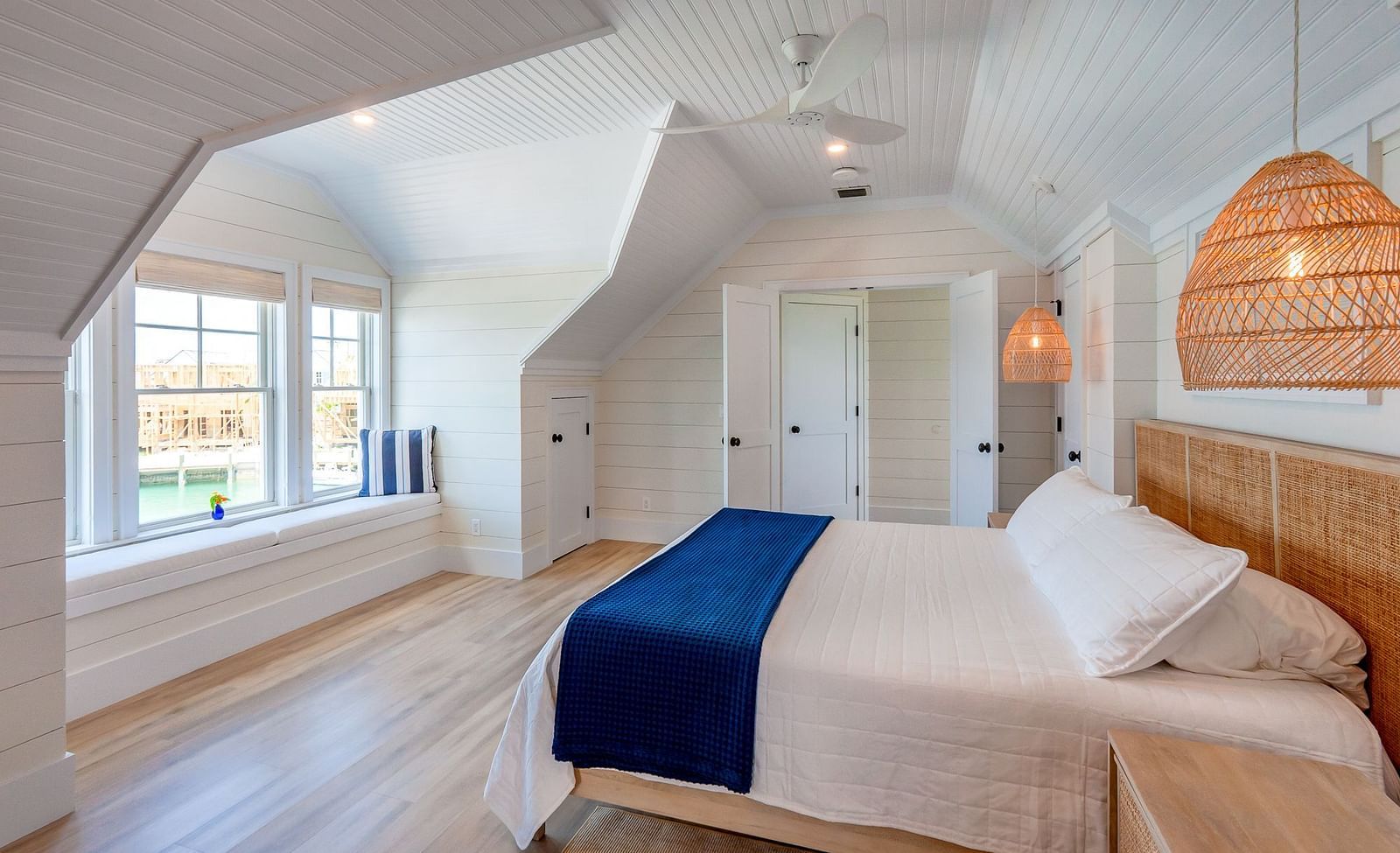 Bedroom with sloped ceilings, blue bed runner, and woven pendant light | Abaco Inn