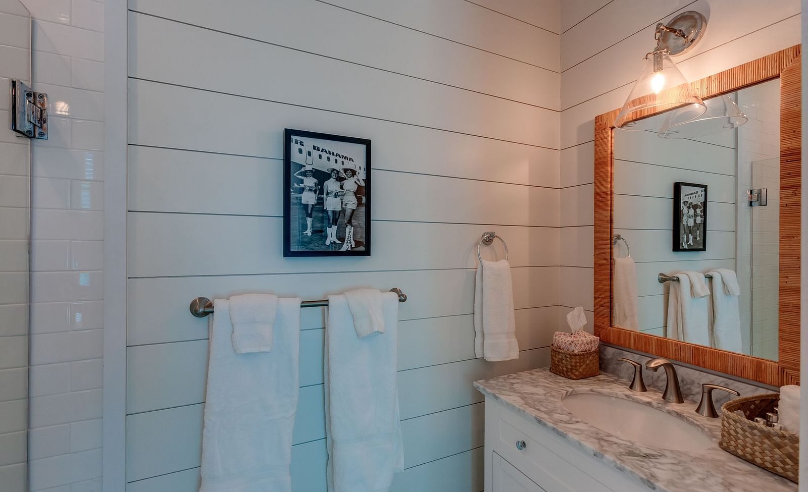Bathroom with a mirror, wash basin, white towels, and framed artwork | Abaco Inn