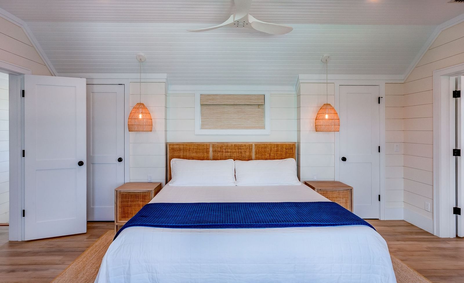 Bedroom with white walls, blue bed runner, and wooden accents | Abaco Inn