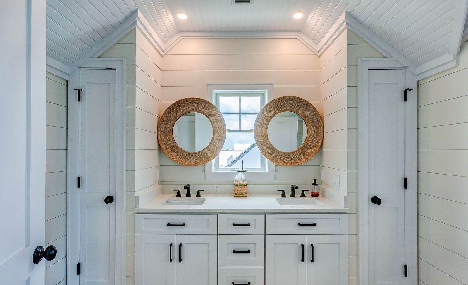 White bathroom with double vanity sinks and circular mirrors | Abaco Inn