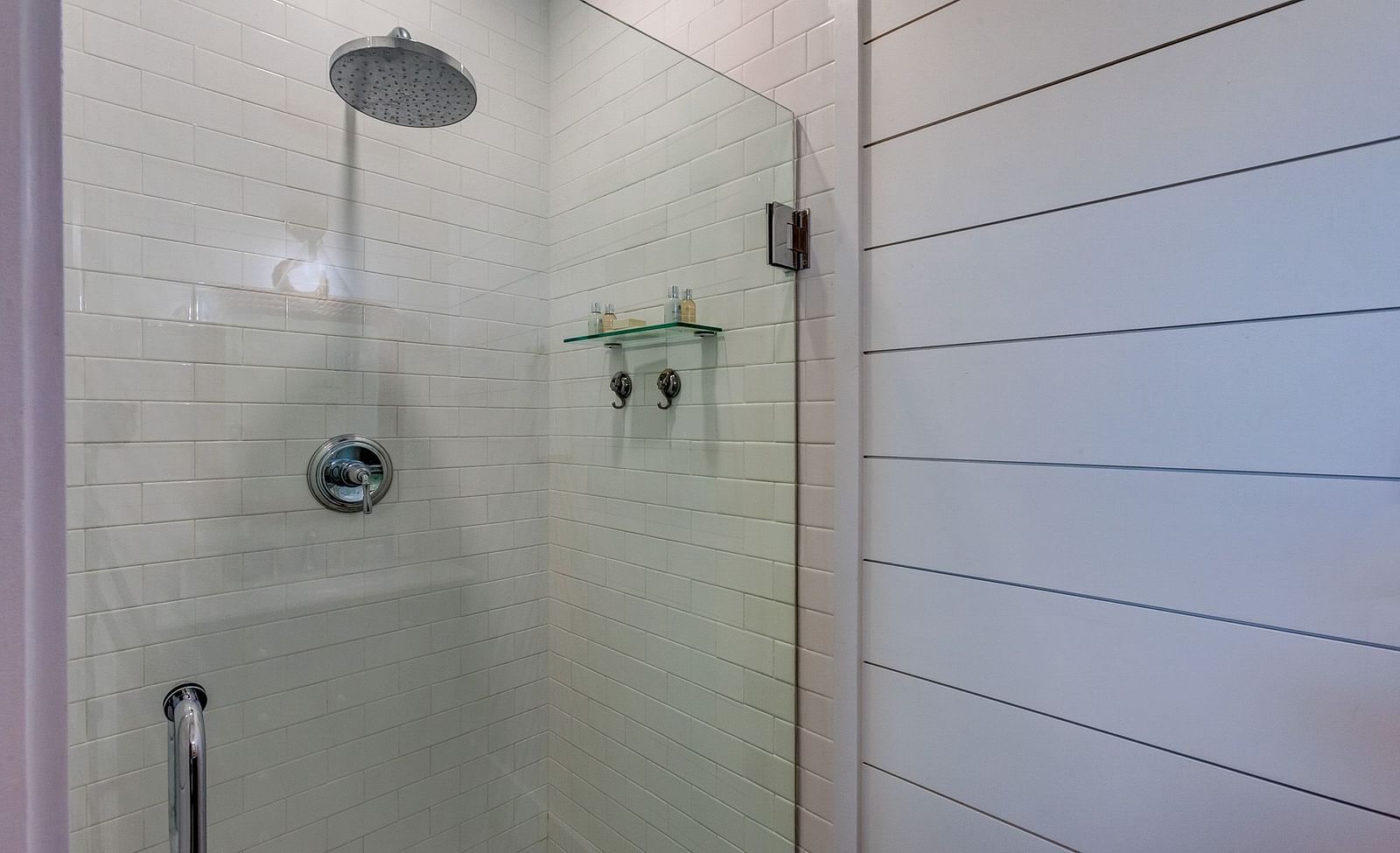 Glass-enclosed shower with white tiles and a rainfall showerhead | Abaco Inn