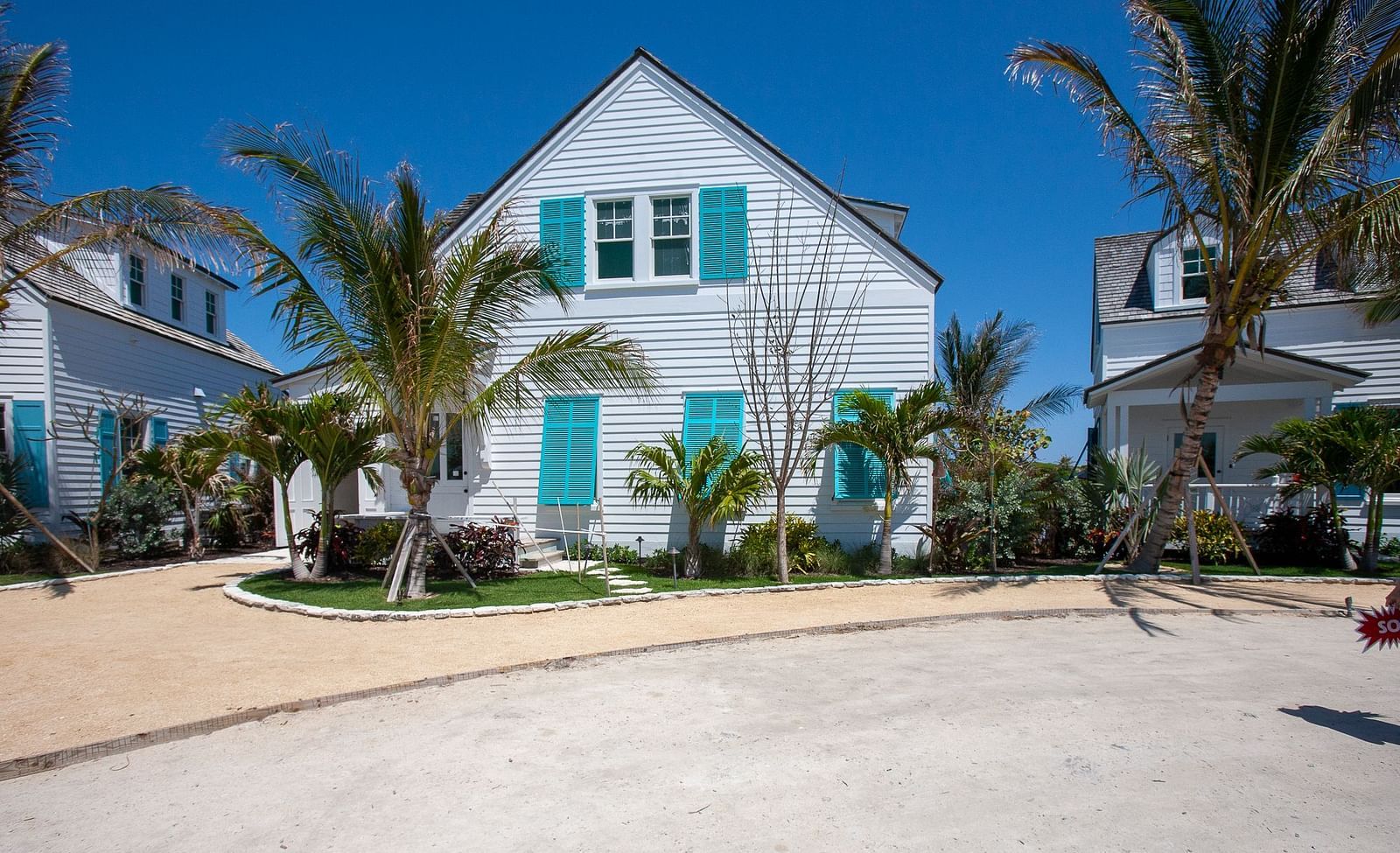 Exterior view of a white coastal home with turquoise shutters and palm trees | Abaco Inn