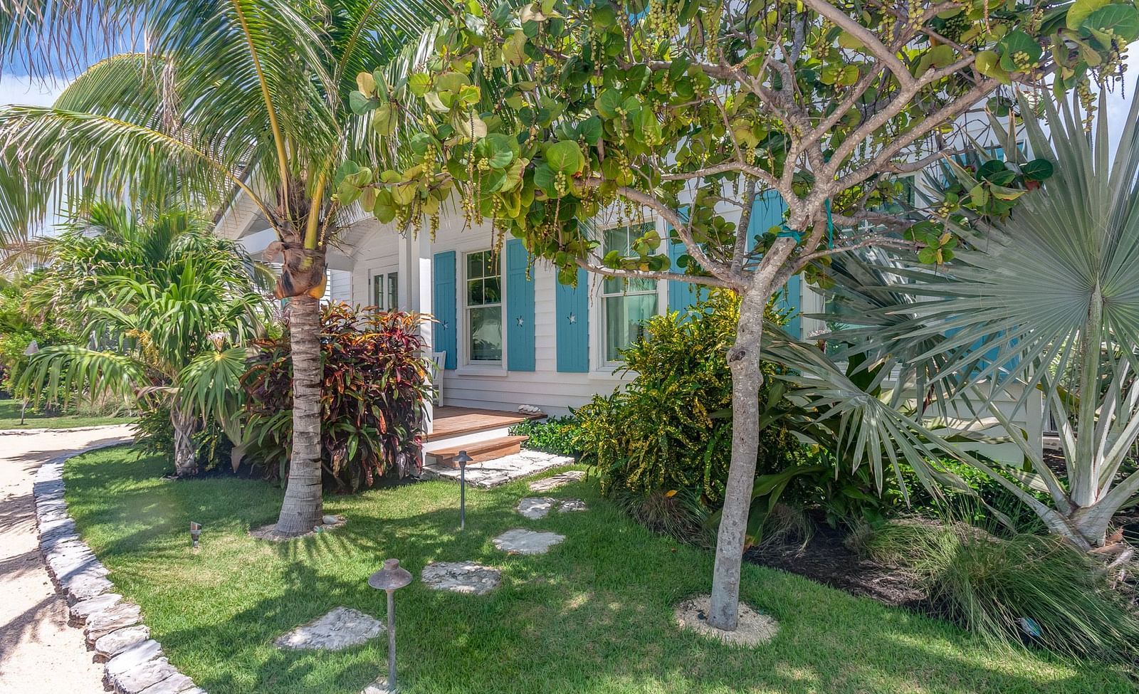 Garden with lush greenery, stone pathway, and an entrance to the cottage | Abaco Inn