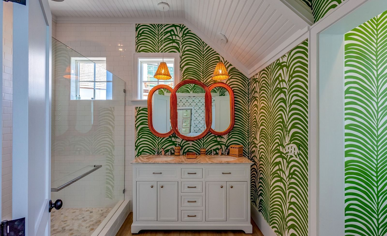 Bathroom with tropical green wallpaper, twin mirrors, and a white vanity | Abaco Inn