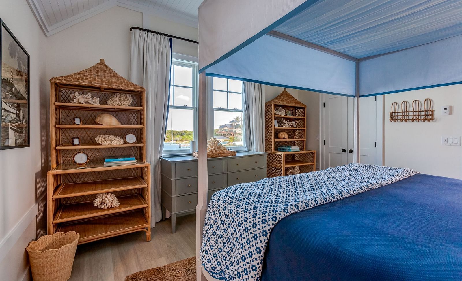 Bedroom with a blue canopy bed, wooden shelves, and ocean views | Abaco Inn