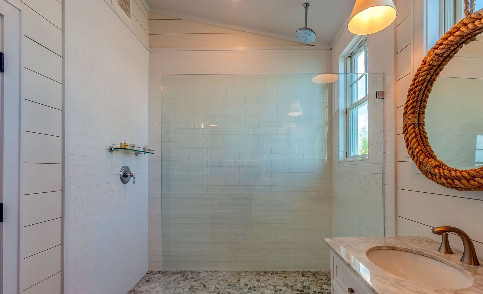 Bathroom with a glass shower, marble flooring, and a woven mirror | Abaco Inn