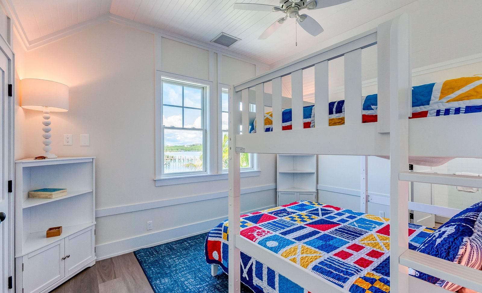 Bunk bed room with colorful bedding, a white dresser, and a window | Abaco Inn