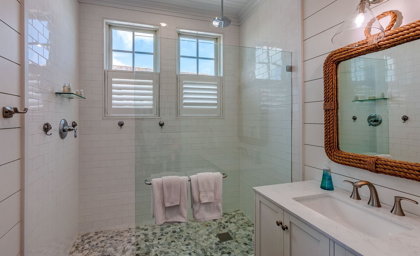 Bathroom with a walk-in shower, white vanity, and two pink towels | Abaco Inn