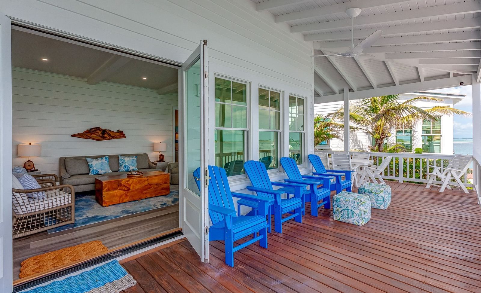 Lounge area opening onto a wooden deck with blue chairs and a sea view | Abaco Inn