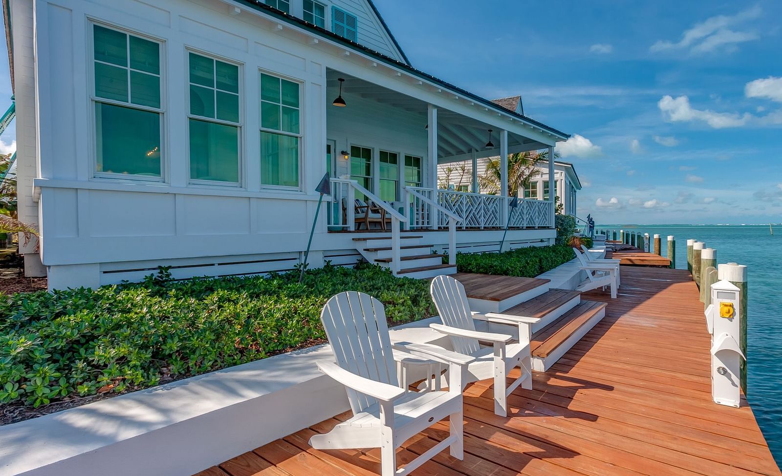 Oceanfront deck with white chairs overlooking the sea and greenery | Abaco Inn