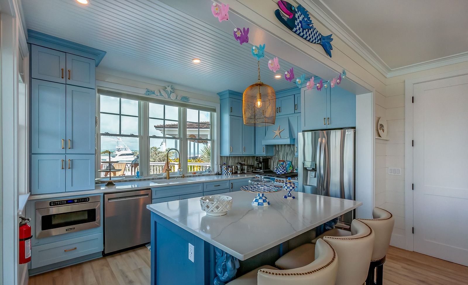 Bright, airy , white and blue coloured theme kitchen with a  table, chairs and windows that overlook the sea at Abaco Inn.