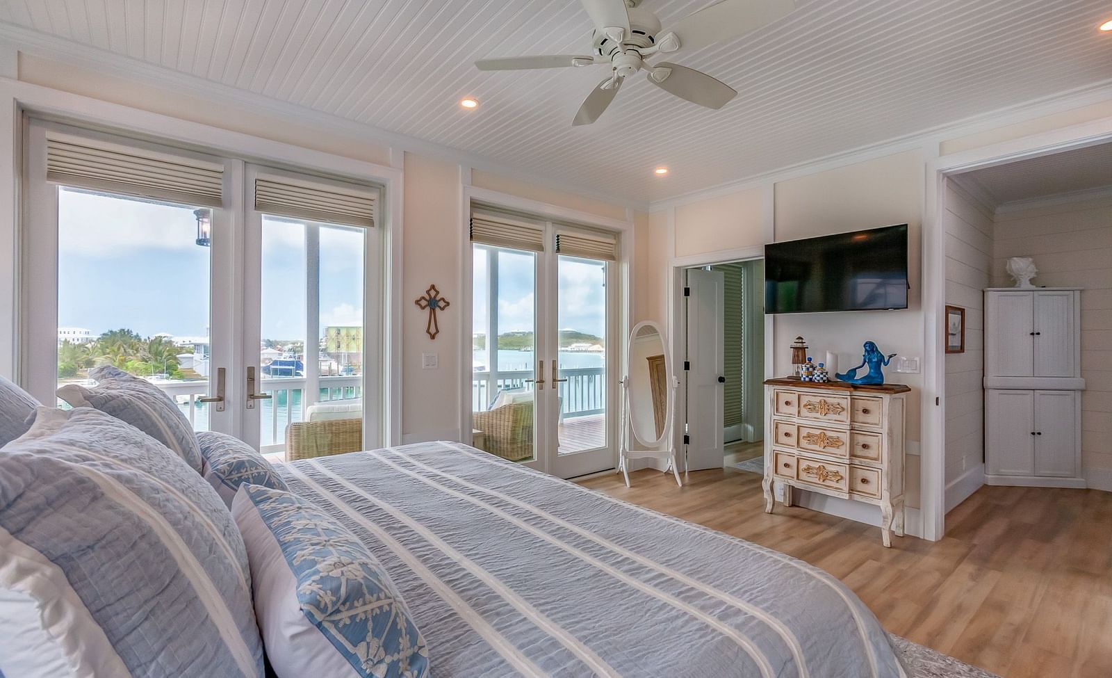 A bright, airy bedroom with a huge bed, TV, cupboard, wardrobe, Ceiling fan and glass doors  that overlooks the sea at Abaco Inn.