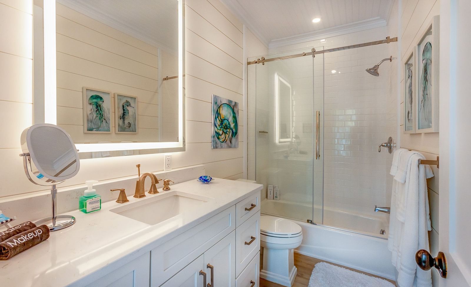 a well lit bathroom with drawers, a huge mirror, a commode and a walk in shower  at Abaco Inn.