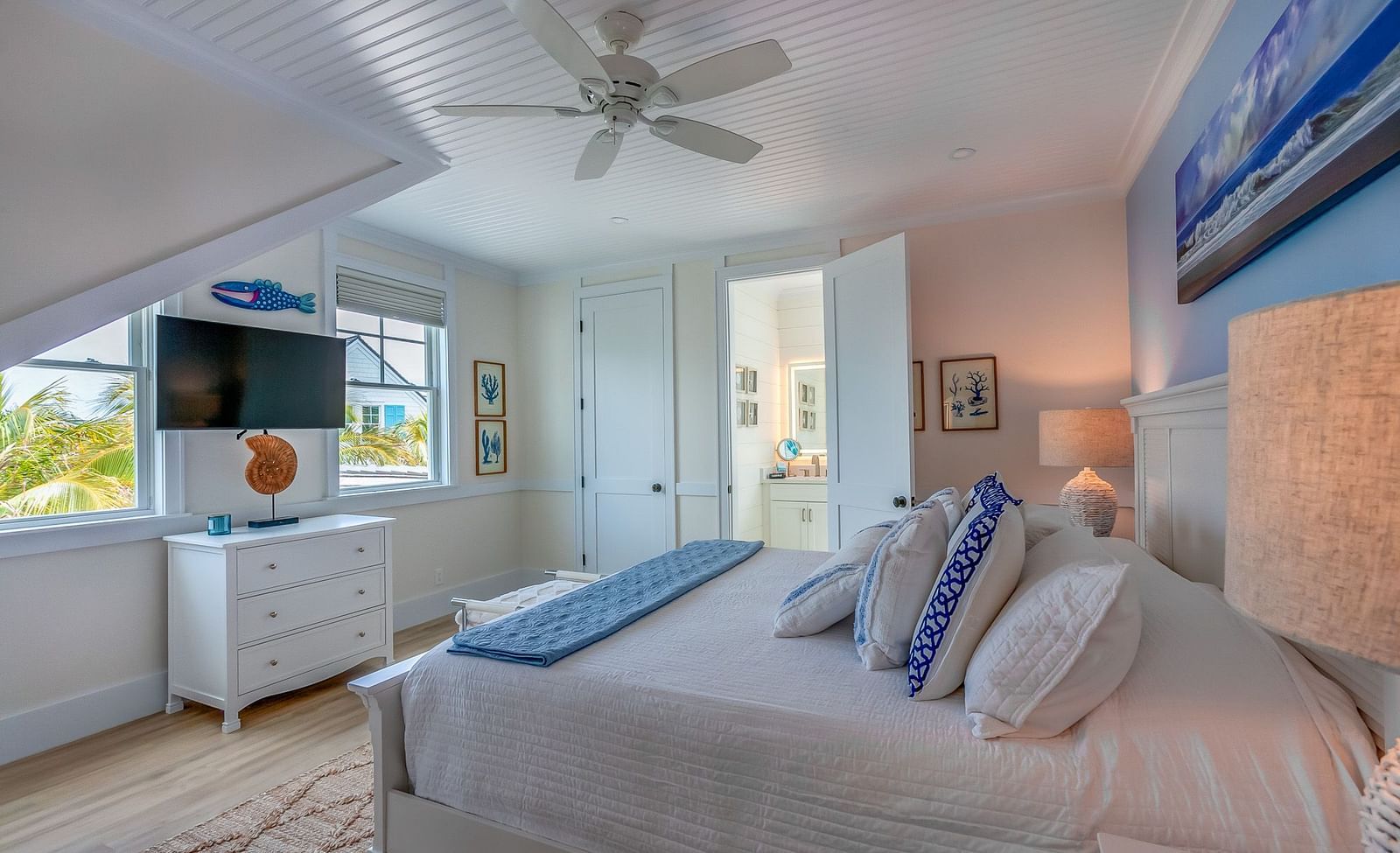 a bright bedroom with a huge bed, drawer, ceiling fan, TV, and windows at Abaco Inn .