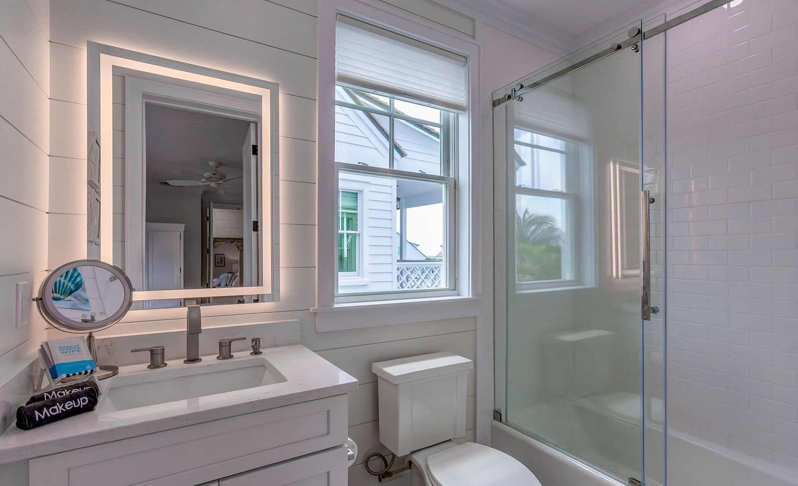 a bathroom with a sink, a huge mirror, a commode, a walk in shower and a window at Abaco Inn.
